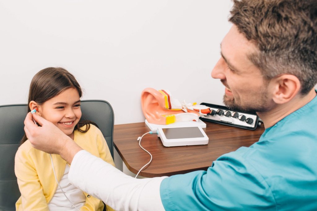 Çocuk odyologu, küçük bir hastayla oyun oynarken işitme testi yapıyor. Çocuk işitme, işitme testi, odyolog, pediatrik işitme.